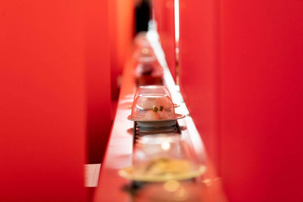 tray with red curtains around. Go along the conveyor belt at this Japanese restaurant