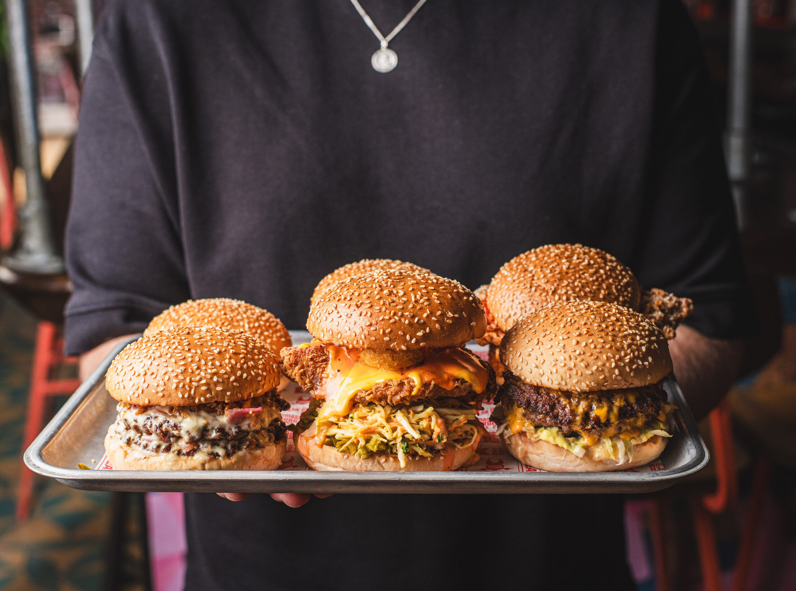 person holding tray with six delicious looking burgers at Meatliquor