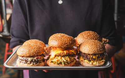 person holding tray with six delicious looking burgers at Meatliquor