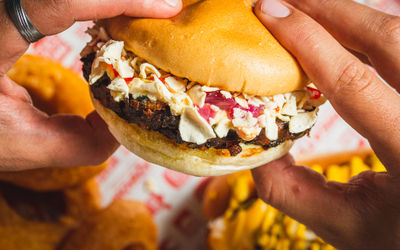 close up shot of hands holding delicious looking meat and cheese burger