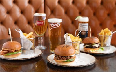 three different burgers on the white plates served with fries and beer at the Metropole