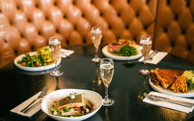 black circle shaped table laid out with four dishes and four glasses of fizz at Brighton Metropole Bar. Bottomless brunch Brighton guide