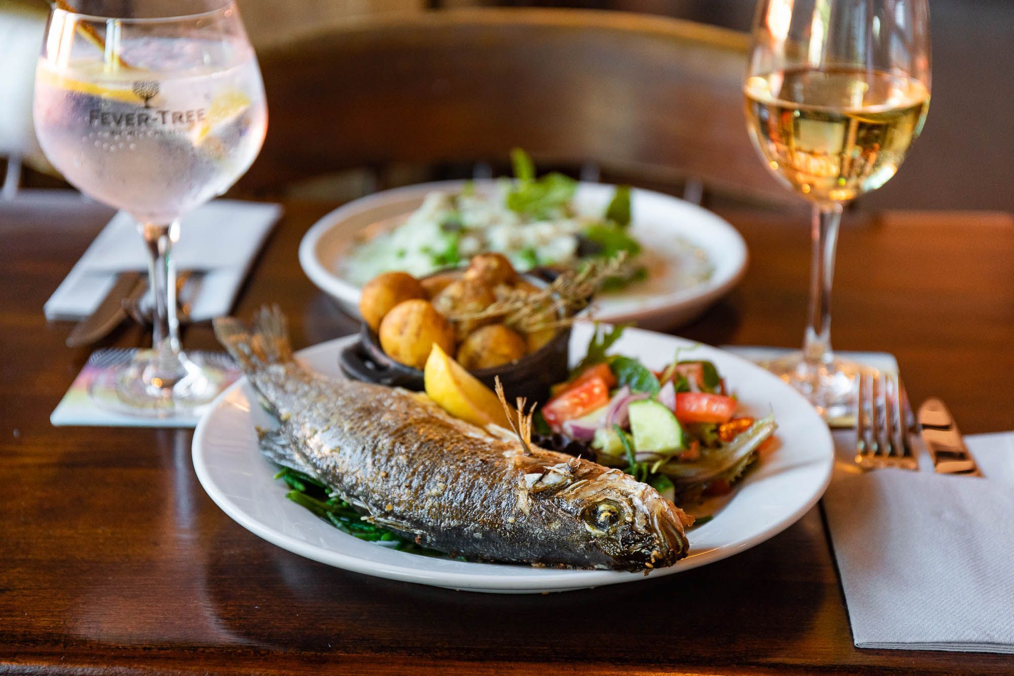 fish and cooked vegetables served on the table with glass of red wine