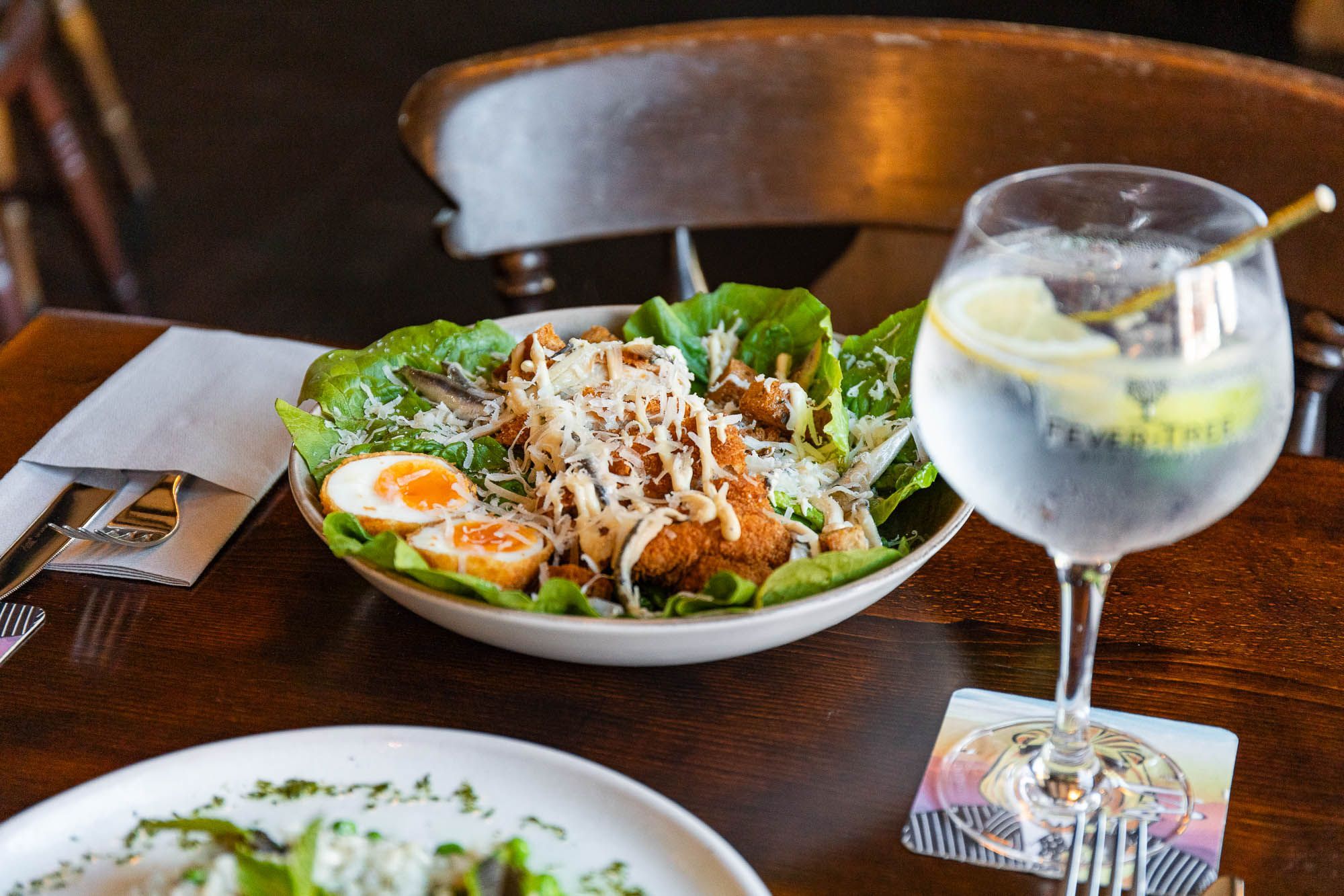 fried egg and meat on the green salad served in white plate with fizzy drink