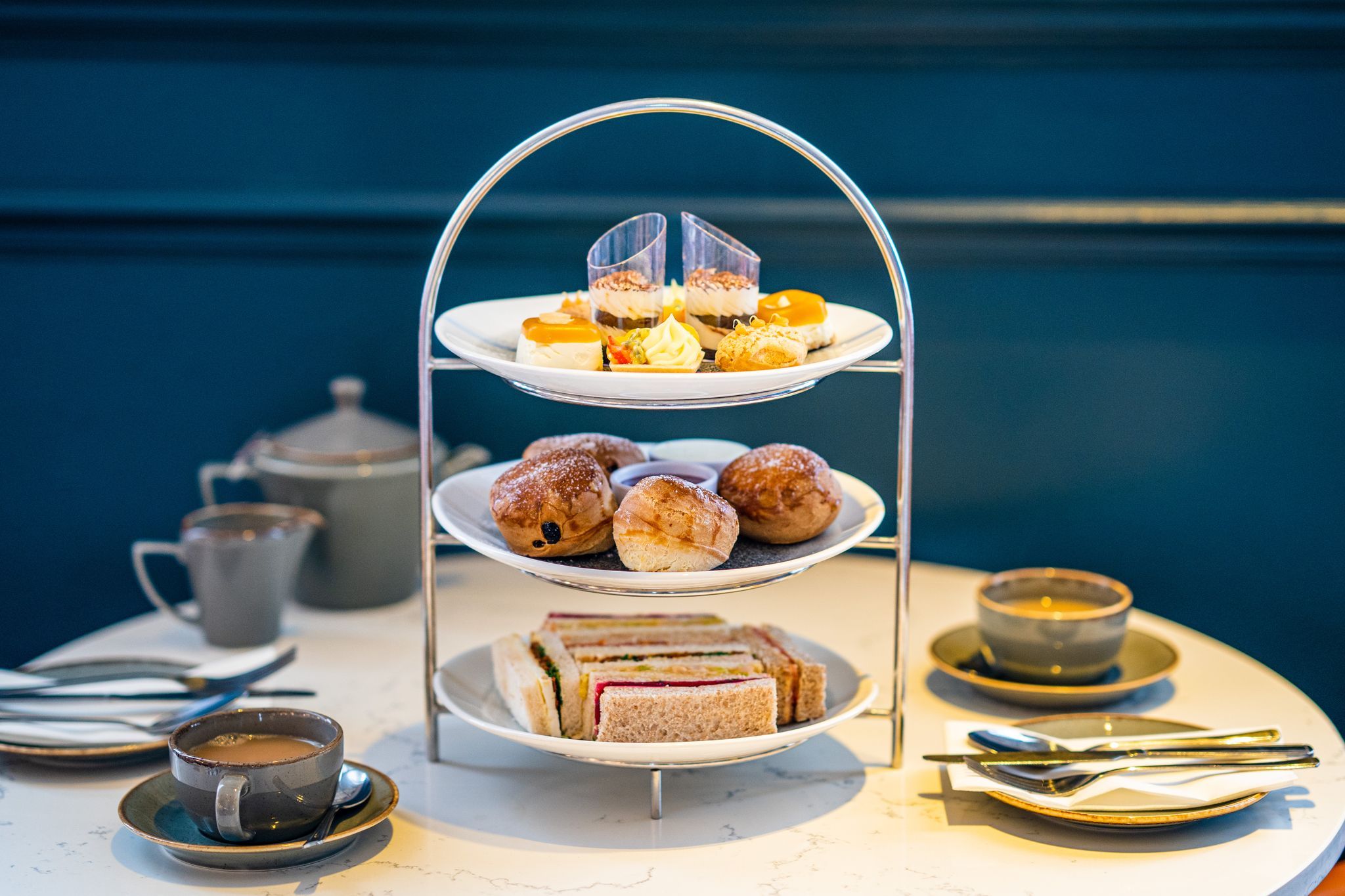 Afternoon tea at Metropole Bar. Sweet little cakes on the three plates with coffee and tea on the table