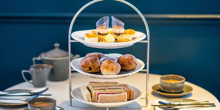 Afternoon tea at Metropole Bar. Sweet little cakes on the three plates with coffee and tea on the table