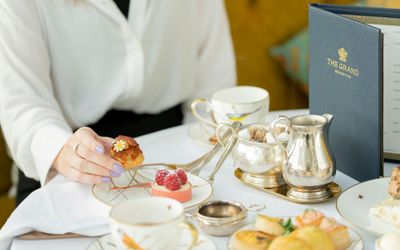 woman having an afternoon tea at the grand Brighton and holding small cake