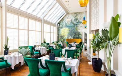 beautiful terrace area at the Grand Hotel Brighon, tables with white covers, luxury green chairs and lively plants as decorations