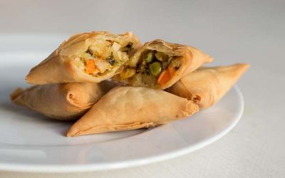 Samosas served on white plate and table