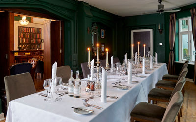 atmospheric dark green room with a set table for ten. Candelabras and dinner place settings