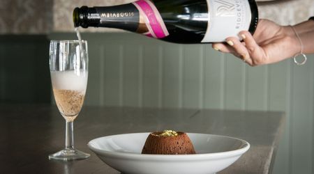Sparkling rose being poured into a champagne flute with a chocolate dessert.