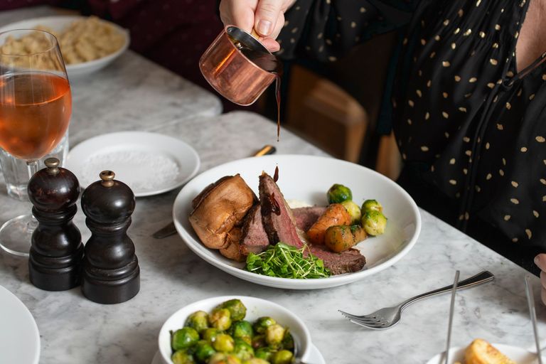 person pouring gravy on the roast, Brussel sprouts served in mini bowl