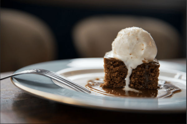 Sticky toffee pudding with ice cream served on a blue plate
