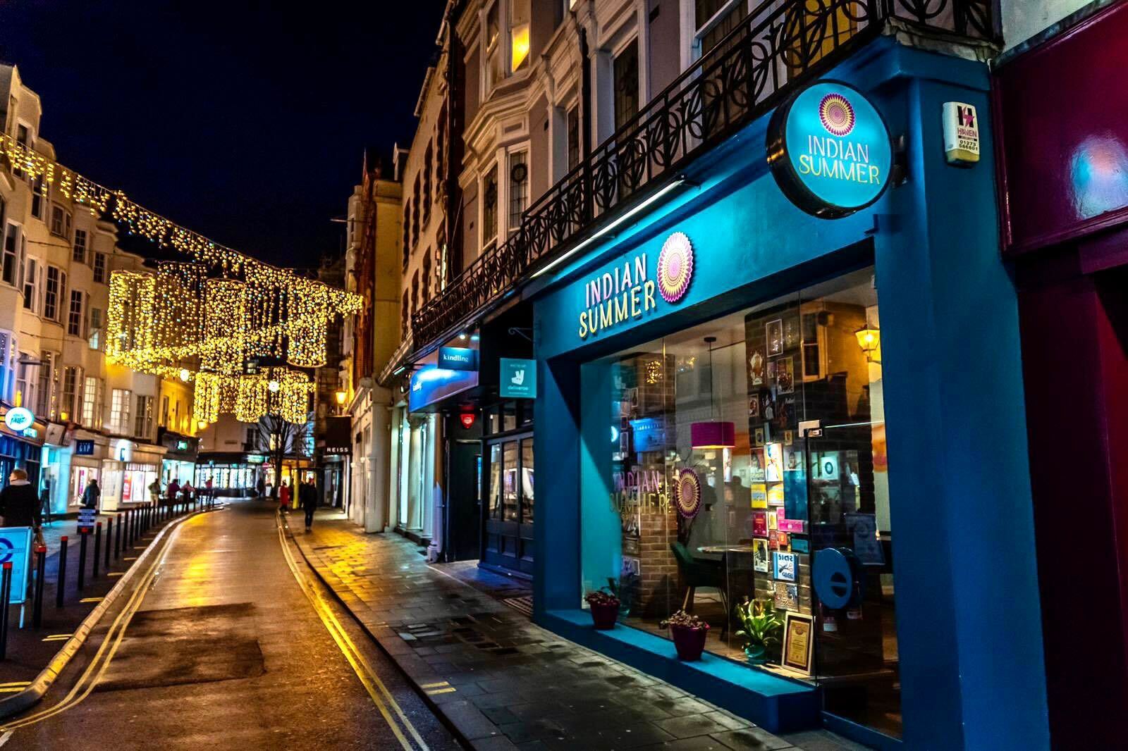 the blue facade of Indian Summer with twinkly lights in the background. This Indian Restaurant features among the best restaurants in Brighton in 2026.