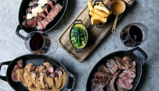 table laid out with prime cut meat dishes in black metal dishes. a side of chips and cheesey broccolli on a wooden board. A lunch in Brighton of epic proportions. Located in the Lanes Brighton