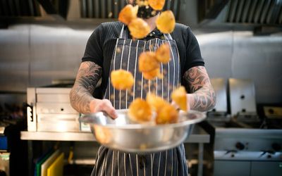 Roast potatoes being flipped by the chef in the kitchen