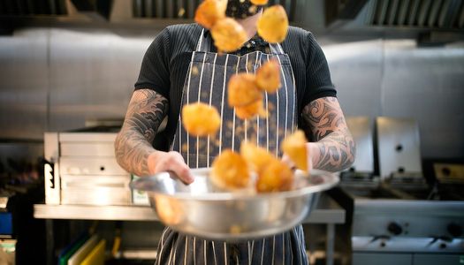 Roast potatoes being flipped by the chef in the kitchen