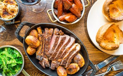 Sharing roast beef with sides including roast potatoes, carrots and Yorkshire puddings