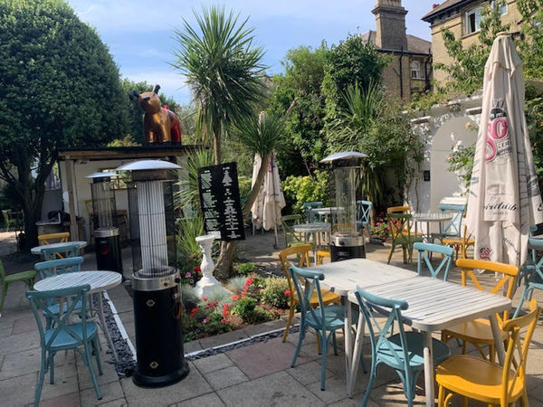 Picturesque summer beer garden with plants, palm trees and statues