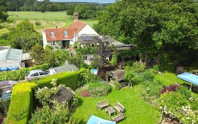 aerial or drone shot of The Jolly Sportsman country pub in Sussex. Pictured the green lawns and countryside surrounding with views of the South Downs National Park.
