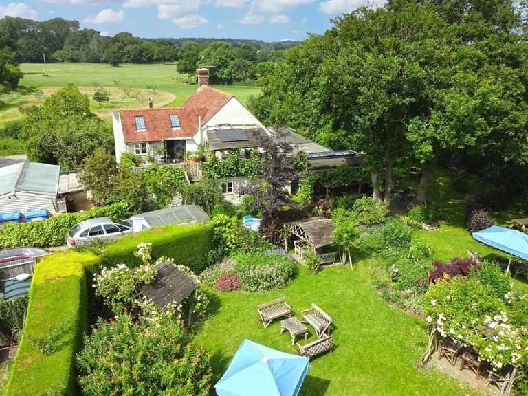 aerial or drone shot of The Jolly Sportsman country pub in Sussex. Pictured the green lawns and countryside surrounding with views of the South Downs National Park.