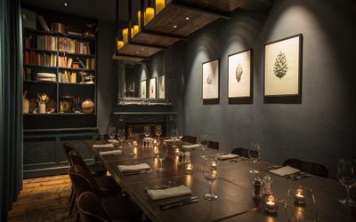 The private dining room Brighton. The Coal Shed, a long room with dark walls and a long wooden table, at the far end is a bookcase full of cookery books.