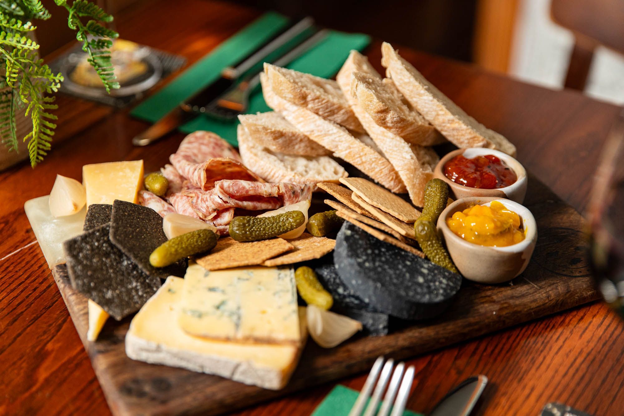 a wooden board with cheese, bread, charcuterie and chutneys on