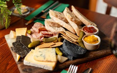 a wooden board with cheese, bread, charcuterie and chutneys on