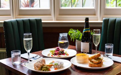 window diner seating with the table laid out with different dishes inludin some cheese and garlic bread, betroot dish, bottle and glasses of wine