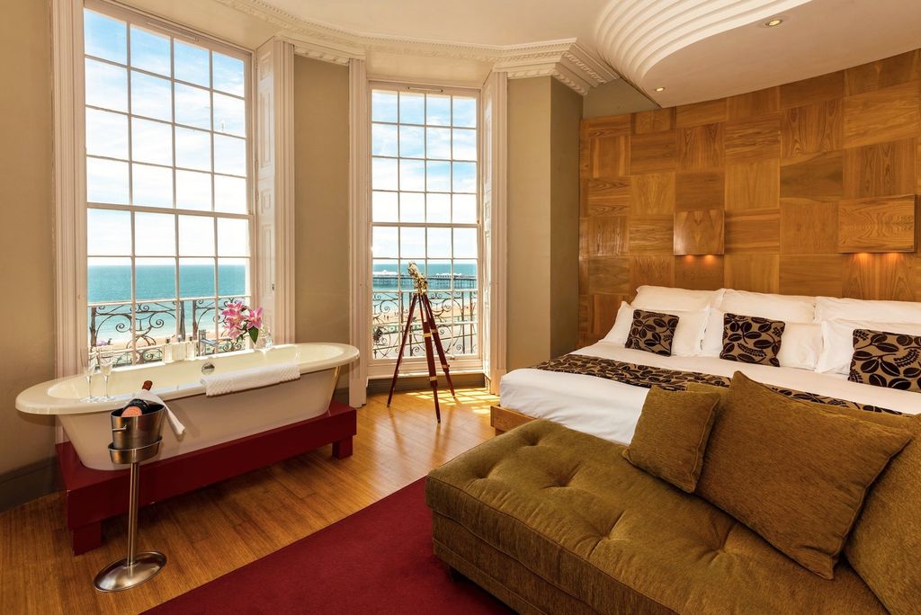A hotel room with sea views, and a bathtub in the bay window iwth an ice bucket of Champagne