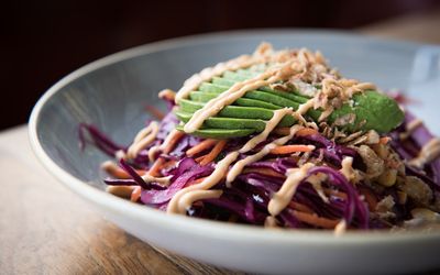 Red cabbage salad with sliced avocado and sauce in a grey bowl