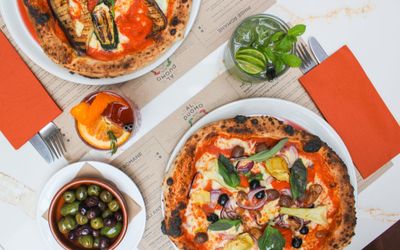 over head shot of two pizzasa bowl of olives and two cocktails. AL Duomo is an Italian restaurant Brighton