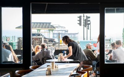 Looking out of the window onto outside seating with the beach in the background. Bottomless brunch Brighton