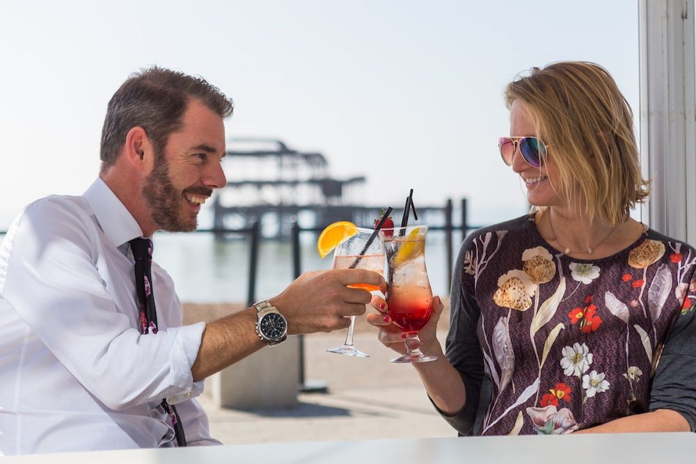 People enjoying cocktails on a sunny day on the terrace with the West Pier in the background. Best bars in Brighton