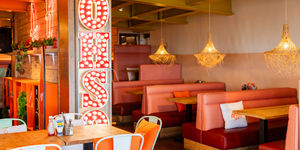 interior shot of the OhSo Brighton, orange seating with wooden tables. Seafront Dining in Brighton
