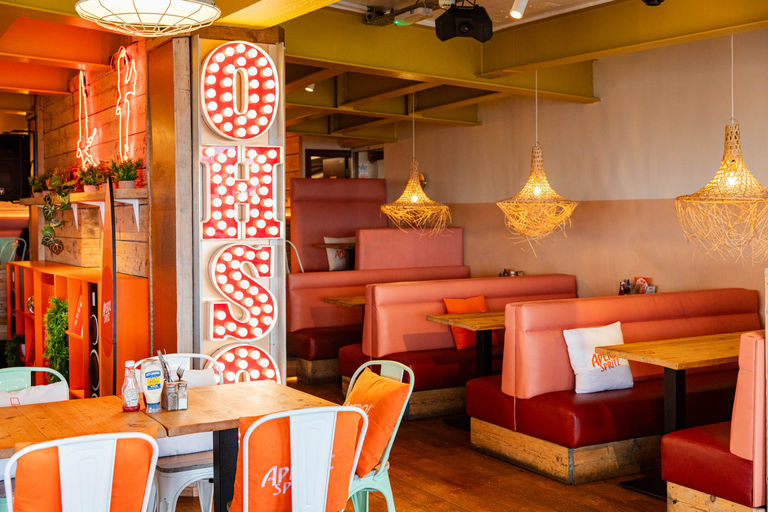 interior shot of the OhSo Brighton, orange seating with wooden tables