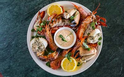 A large seafood platter with lobster, crab and scallops. Served on a large round tray with a seafood dip and fresh lemon.