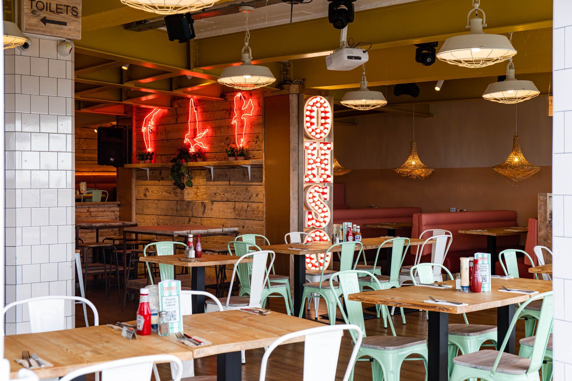 interior shot of the Ohso Brighton. Long wooden tables with mint metal chairs