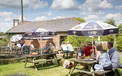 Countryside beer garden with people sitting at tables with parasols