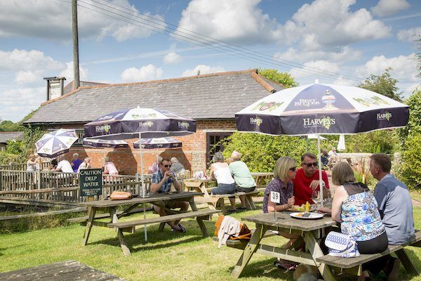 Countryside beer garden with people sitting at tables with parasols