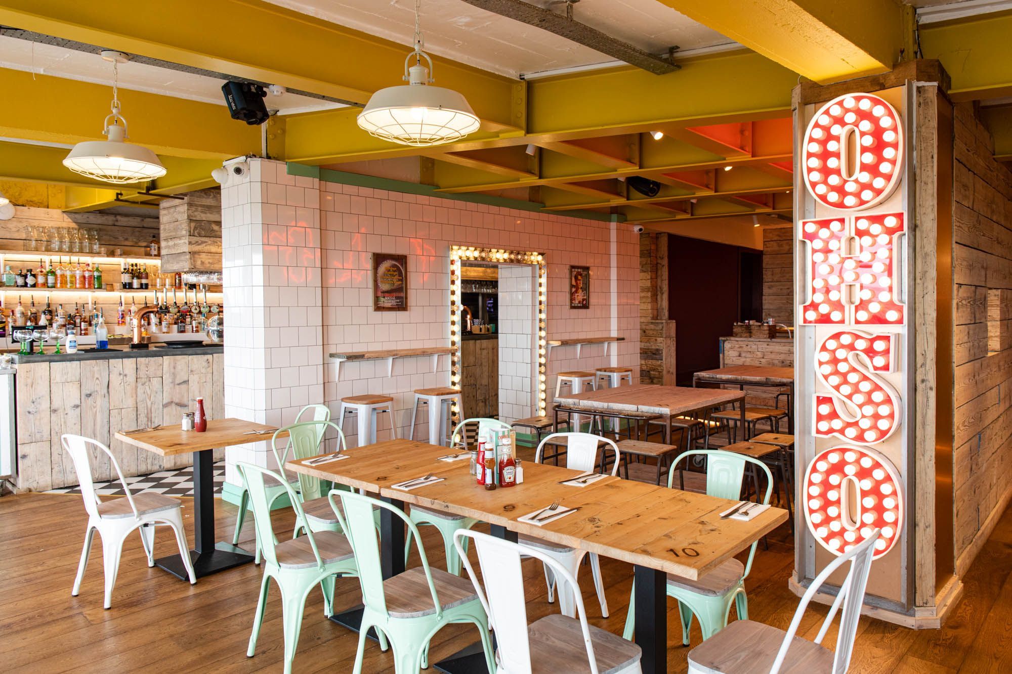 interior shot of the Ohso Brighton. Long wooden tables with mint metal chairs