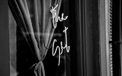 Black and white image of the window of the set restaurant. Neon light is switched off and shows the words The Set in cursive writing. A stylish image for one of Brighton's best restaurants.