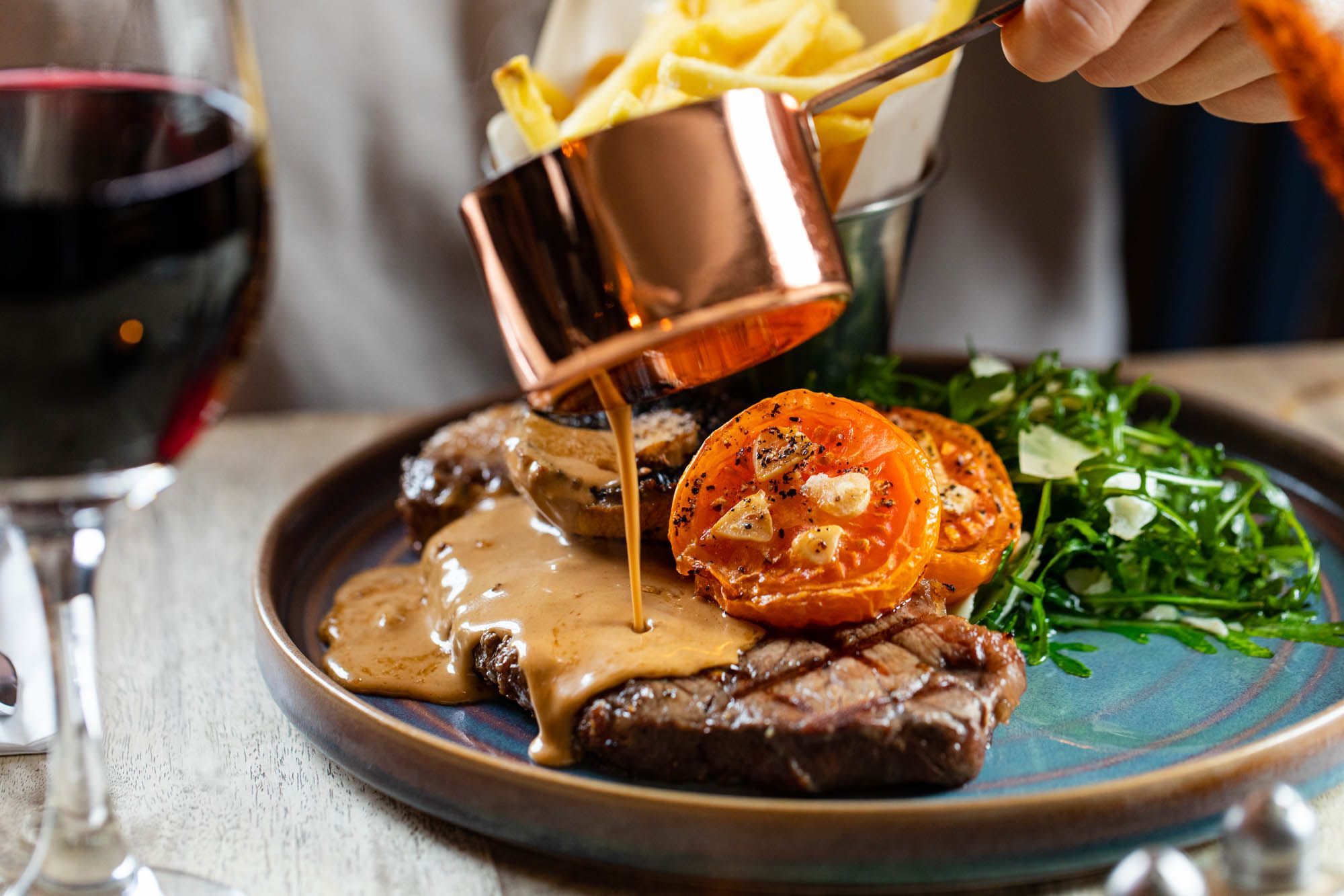 brown gravy being poured on the piece of cooked meat served on the light blue plate at The Sportsman Pub