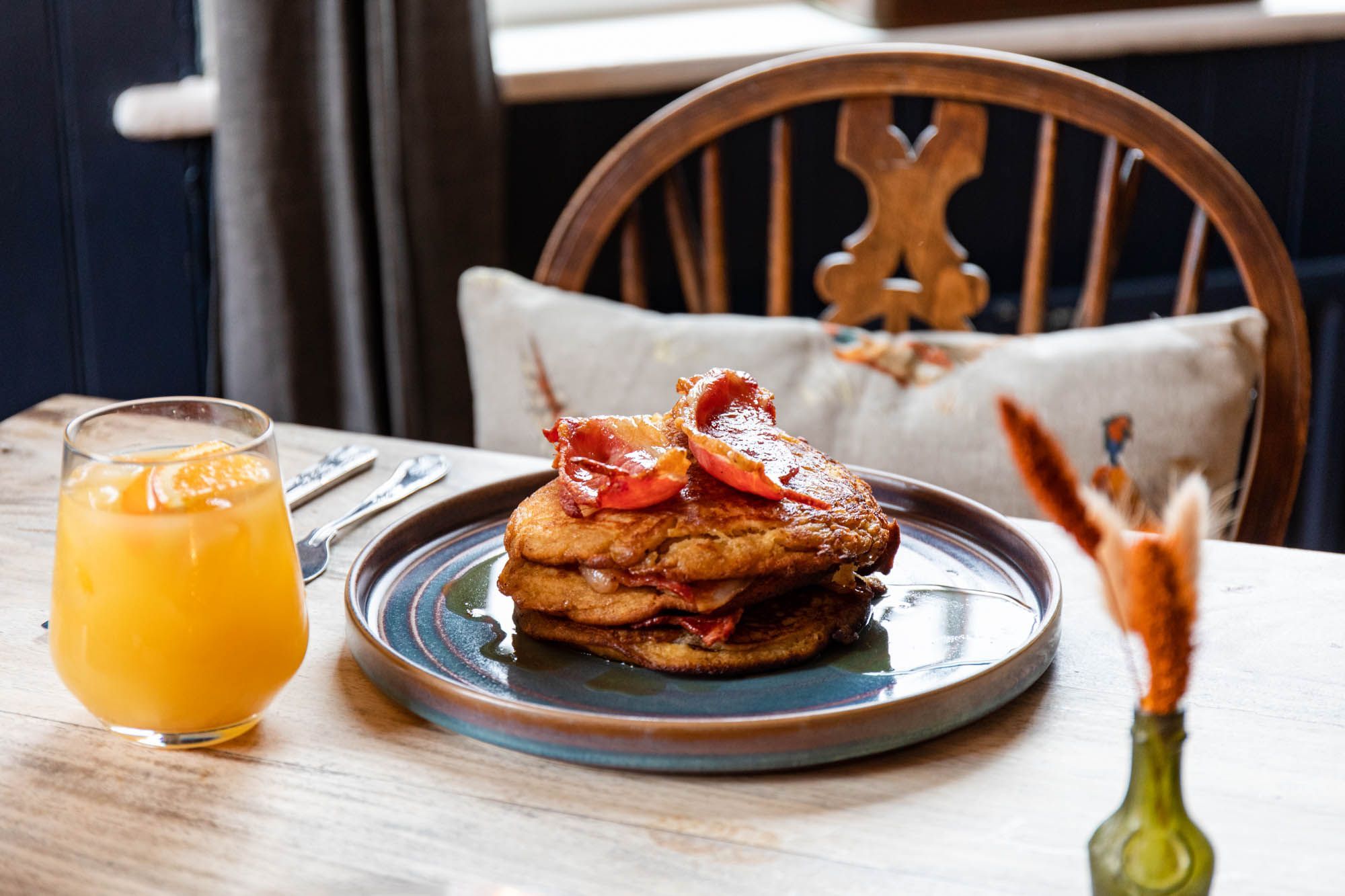 delicious looking American pancakes with bacon strips, covered on syrup and served with glass of orange juice