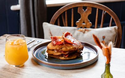 delicious looking American pancakes with bacon strips, covered on syrup and served with glass of orange juice