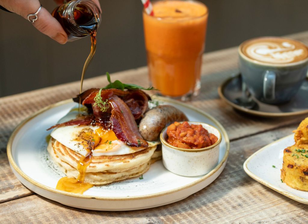 american pancakes served with eggs, bacon and beans on white plate