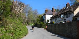 Cyclists riding along a country lane passed the pub on a bright Summers day. Pubs in Sussex, Sussex Downs National Park.