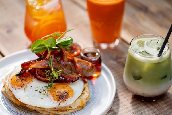 close up shot of pancakes with eggs an bacon on served with red drinks. Moksha Brighton