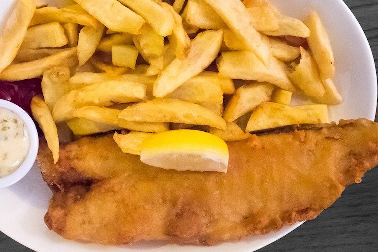 fish and chips on a white plate with a slice of lemon on top