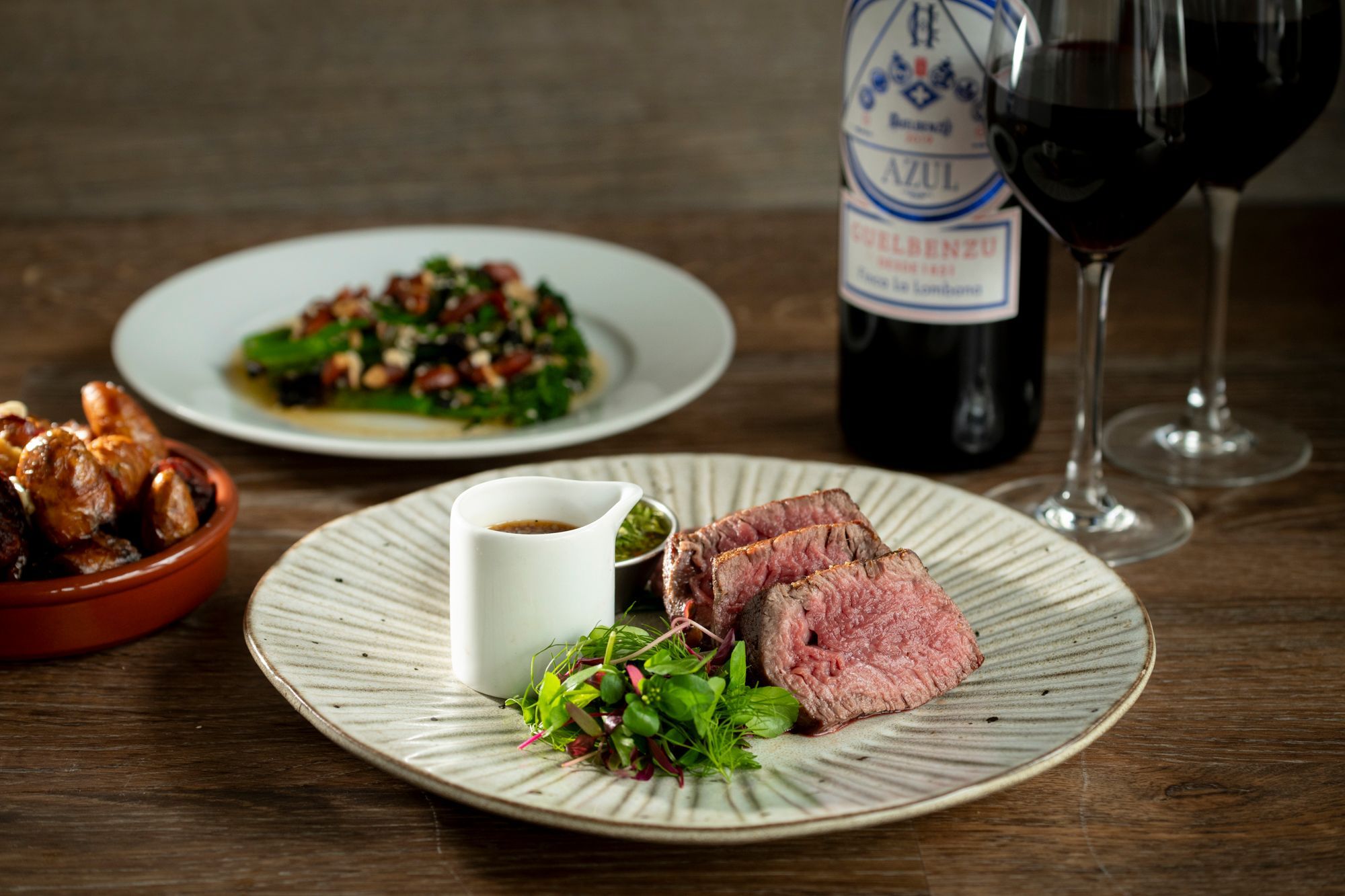 two pieces of steak served with gravy and greens on the white plate at the Market Restaurant